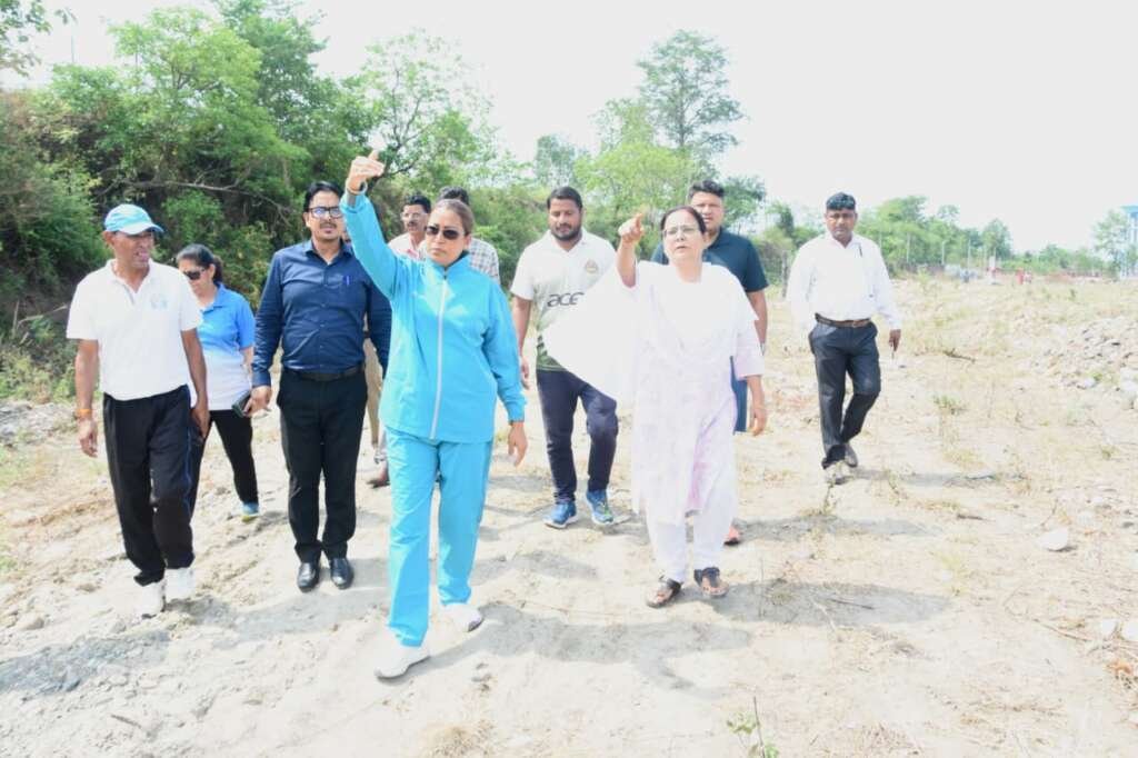 गौलापार स्थित खेल विश्वविद्यालय की भूमि पर निरीक्षण के दौरान मिट्टी माथे से लगाती और अधिकारियों के साथ स्थल का जायजा लेती खेल मंत्री रेखा आर्या।