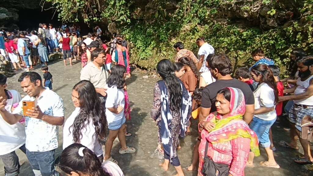 गुचुपानी में पर्यटक ठंडे पानी और प्राकृतिक गुफाओं के बीच घूमते हुए।