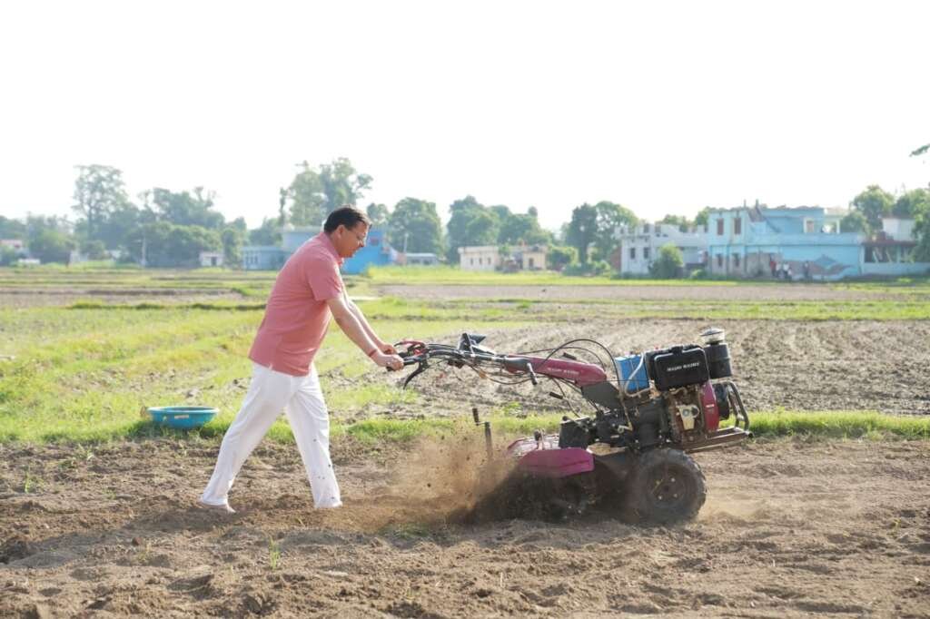 सीएम धामी खेत में टिलर चलाते हुए।