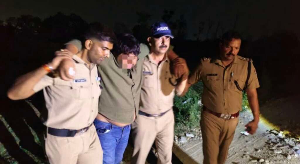 देहरादून में पुलिस मुठभेड़ में घायल बदमाश पुलिस हिरासत में, आसपास मौजूद पुलिसकर्मी।