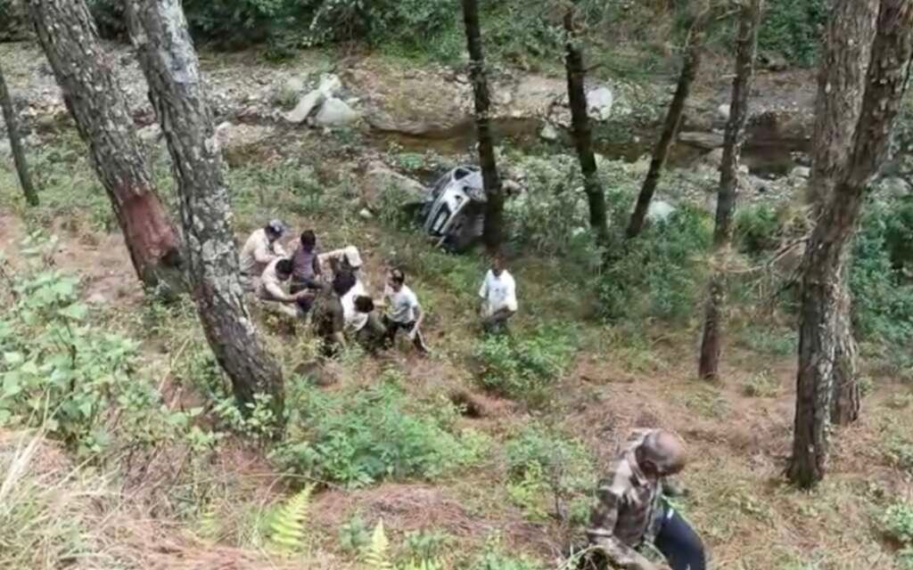 अल्मोड़ा में सड़क हादसे के बाद खाई में गिरी कार से घायलों को निकालते स्थानीय लोग और पुलिस।