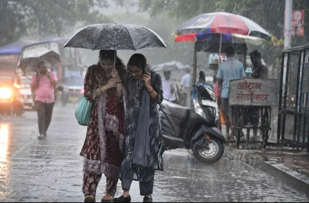 उत्तराखंड में भारी बारिश के दौरान छाता लेकर जाती महिलाएं