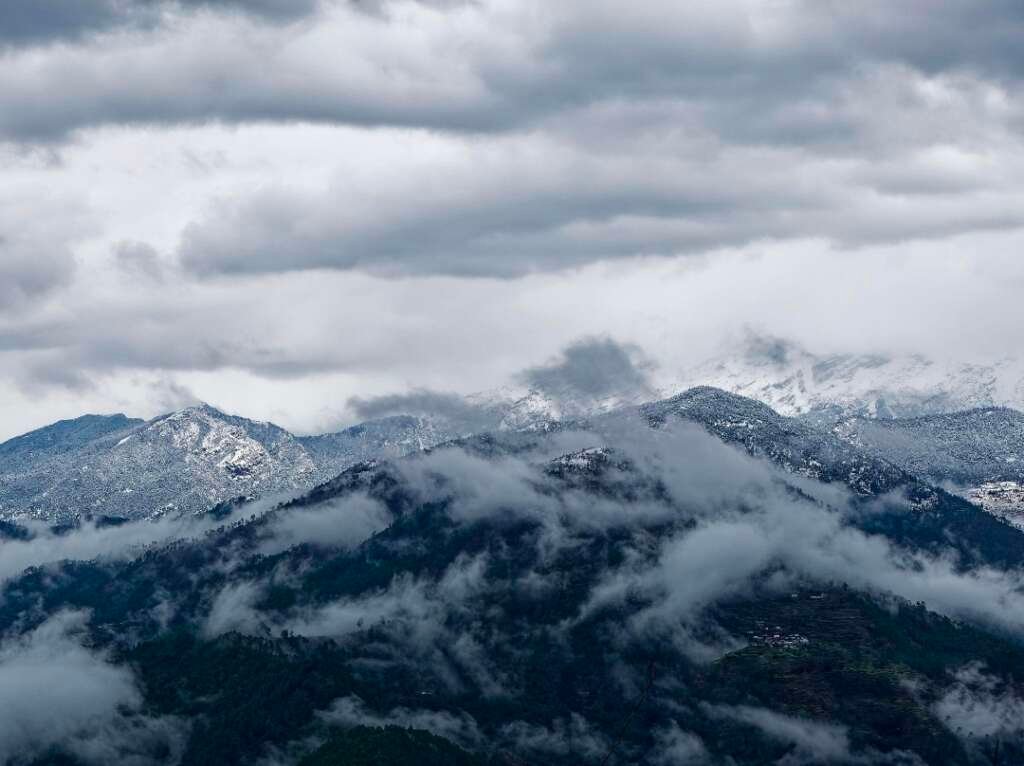 Uttarakhand Himalayas with cloudy skies and snow-covered mountain peaks